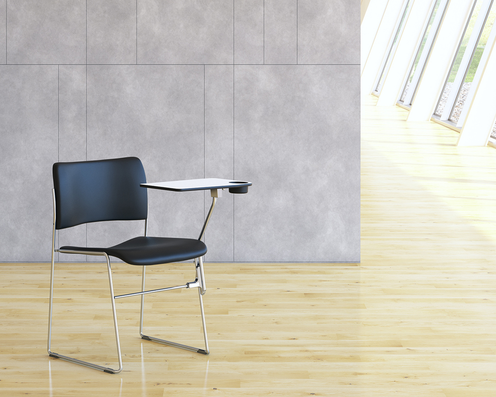 A picture of the black 40/4 chair with a white writing tablet against a grey wall, and on a wooden floor