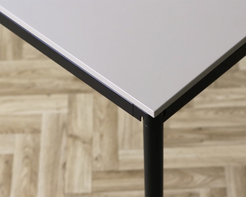 A close-up of a Simpla tabletop corner on a wooden floor